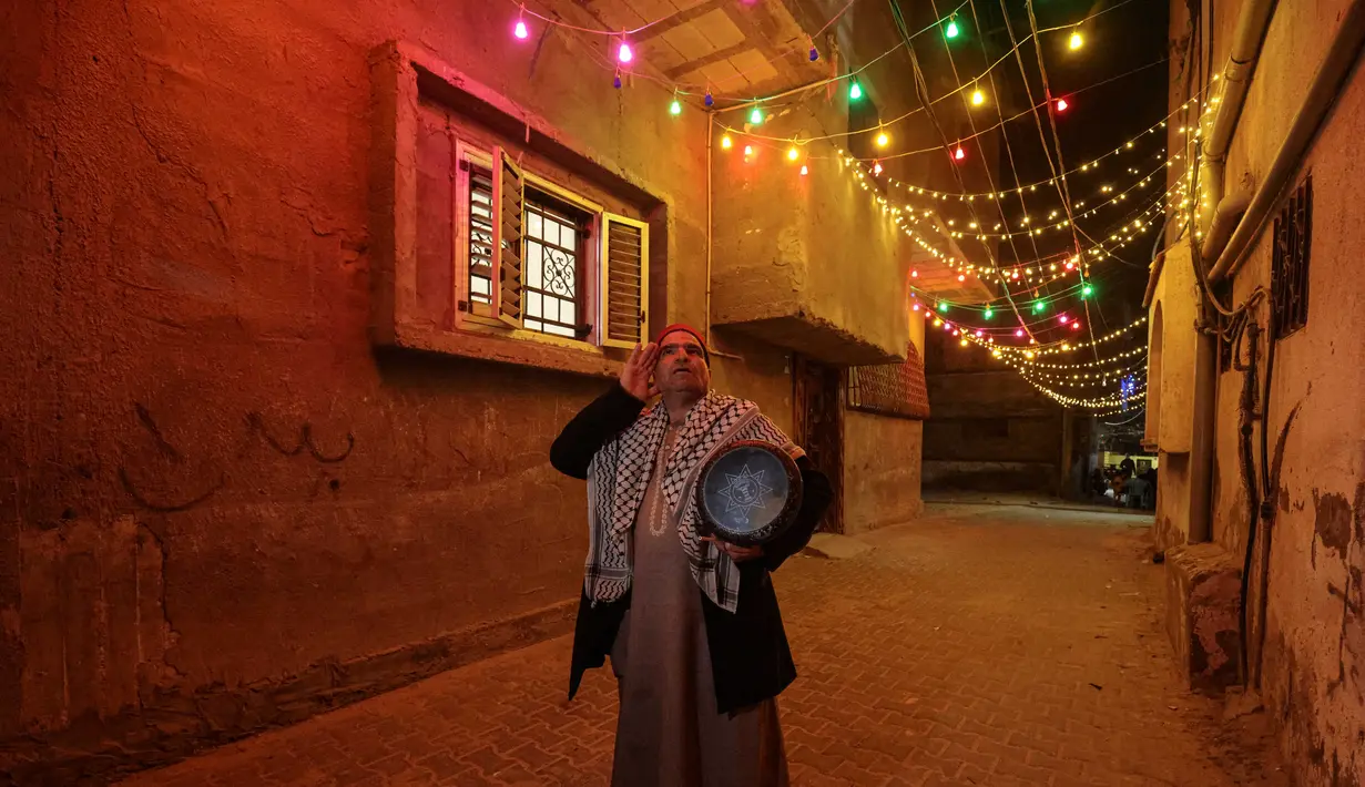Nizar al-Dabbas Palestina berusia lima puluh tahun, seorang "Musaharati" yang memainkan peran tradisional sebagai "penabuh drum Ramadhan", membangunkan umat Islam untuk makan sahur sebelum fajar selama bulan suci Ramadhan di Khan Yunis di Jalur Gaza selatan (5/4/2022). (AFP/Said Khatib)