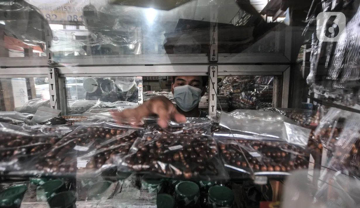 Pekerja merapikan aneka tasbih dan gelang khas Mekkah di etalase toko di Jalan Raya Pondok Gede, Jakarta, Rabu (21/7/2021). (merdeka.com/Iqbal S. Nugroho)