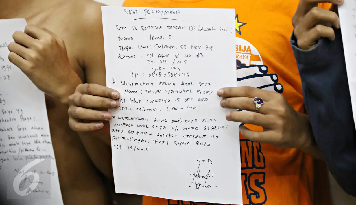 Salah seorang anak menunjukkan surat pernyataan yang dibuatnya di Polda Metro Jaya, Jakarta, Minggu (18/10). Polisi mengamankan ratusan remaja yang berbuat onar menjelang laga final Piala Presiden di GBK. (Liputan6.com/Immanuel Antonius)