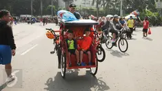 Seorang Warga Negara Asing mengendarai becak saat Hari Bebas Kendaraan di Kawasan Bundaran HI, Minggu (7/5). Aksinya ini sempat menarik perhatian warga. (Liputan6.com/Helmi Fithriansyah)