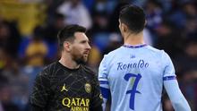 Penyarang Paris Saint-Germain, Lionel Messi (kiri) berjalan melewati pemain Riyadh All-Star, Cristiano Ronaldo, saat laga persahabatan Stadion King Fahd, di Riyadh, Arab Saudi, Jumat (20/1/2023) dini hari WIB. (AFP/Frank Fife)