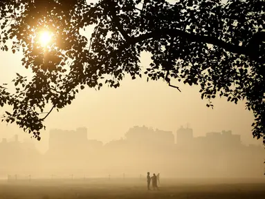 Orang-orang berjalan di pagi berkabut di taman Maidan di Kolkata (29/11/2019). Selama musim dingin, wilayah utara India sering mengalami kabut tebal, menyebabkan penundaan lalu lintas dan mengganggu jadwal penerbangan dan kereta api. (AFP Photo/Dibyangshu Sarkar)