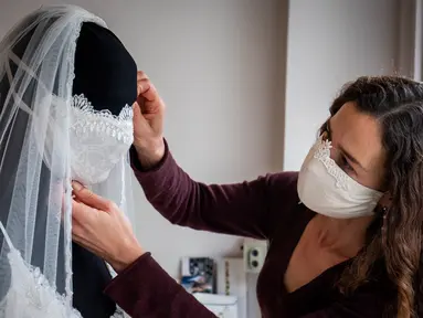 Desainer Friederike Jorzig merapikan masker buatannya di Berlin, Jerman (31/3/2020). Frederike Jorzig membuat gaun pernikahan yang dirancang lengkap dengan masker untuk menghindari penularan Covid-19 di tokonya di distrik Schoeneberg Berlin. (AFP/Odd Andersen)