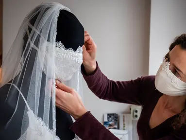 Desainer Friederike Jorzig merapikan masker buatannya di Berlin, Jerman (31/3/2020). Frederike Jorzig membuat gaun pernikahan yang dirancang lengkap dengan masker untuk menghindari penularan Covid-19 di tokonya di distrik Schoeneberg Berlin. (AFP/Odd Andersen)