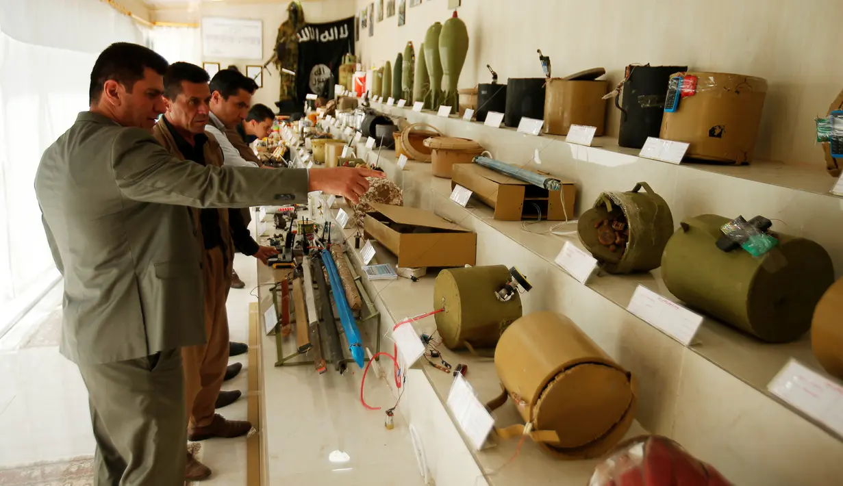 Tentara Kurdi Peshmerga melihat melihat-lihat mortir dan macam-macam bom yang digunakan oleh militan negara Islam (ISIS) di sebuah museum di Erbil, Irak, 12 Mei 2019. 'Museum ISIS' tersebut dibuka oleh militer Peshmerga. (REUTERS/Azad Lashkari)
