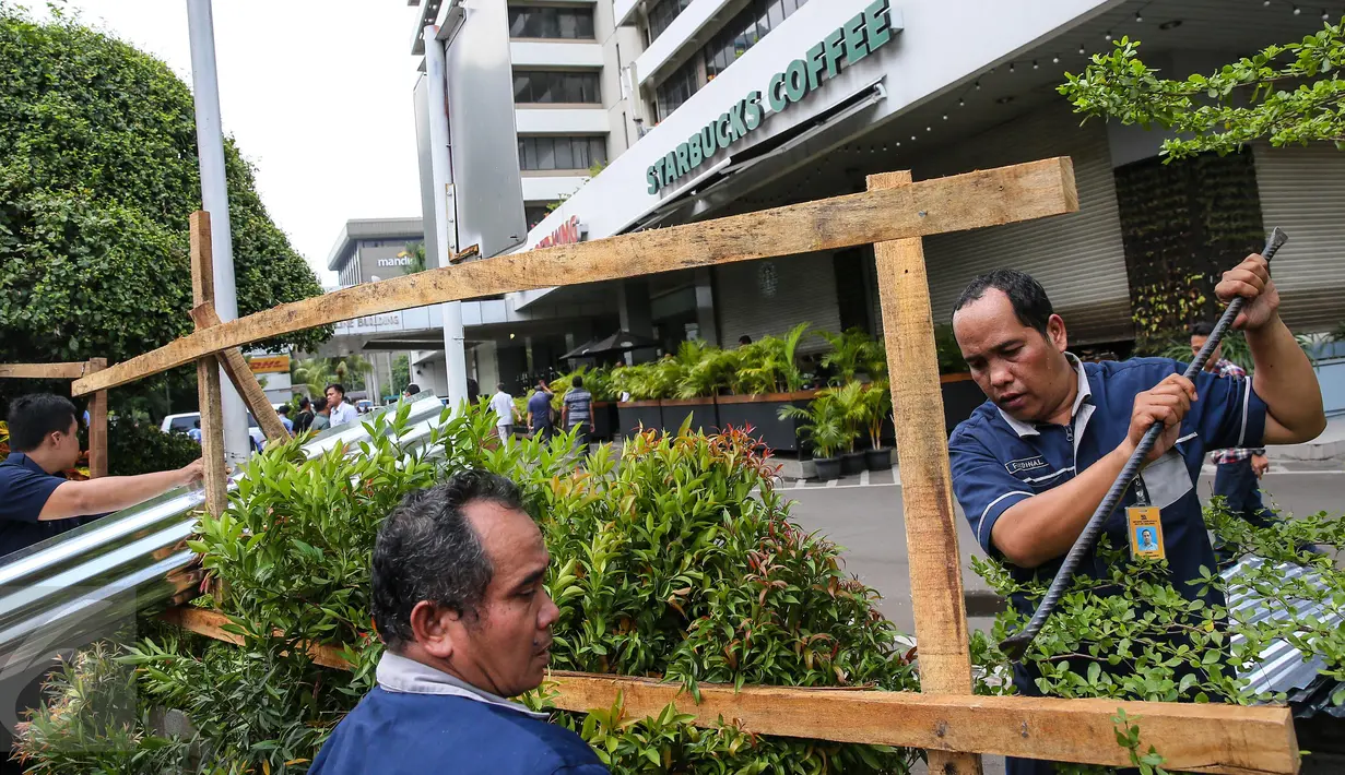 Petugas membongkar seng-seng yang menghiasi depan gerai Starbucks, Jalan MH Thamrin, Jakarta, Jumat (15/1). Seng yang dipaku pada kayu-kayu itu dibongkar petugas. (Liputan6.com/Faizal Fanani)