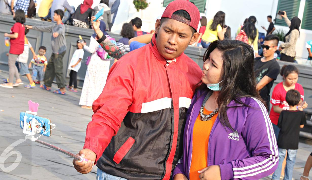 Remaja berfoto bersama saat berwisata di Kota Tua, Jakarta, Minggu (8/5).Dengan latar bangunan tua di kawasan tersebut menjadikan banyak remaja yang mengabadikan gambar mereka. (Liputan6.com/Imma nuel Antonius)