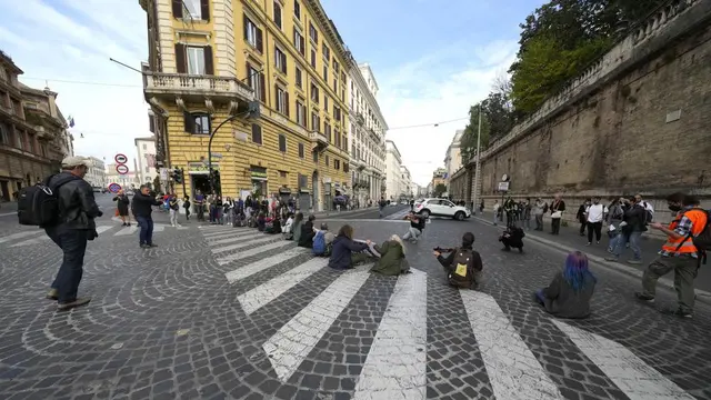 Aktivis dari Extinction Rebellion menggunakan kunci sepeda untuk merantai diri ke pagar sambil memegang tanda selama demonstrasi di luar KTT G20 di Roma, Minggu, 31 Oktober 2021 (AP Photo)