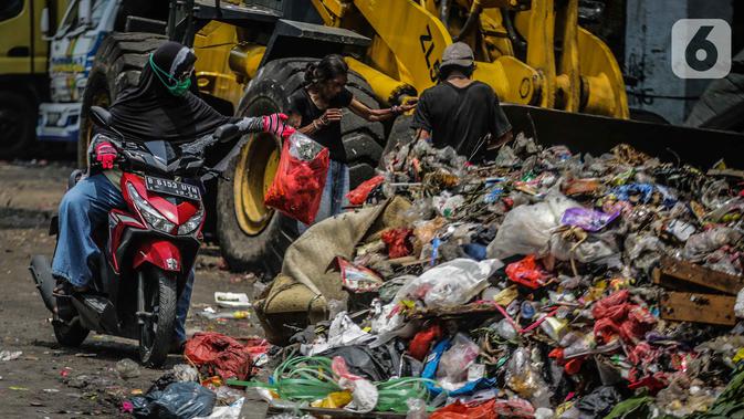 Pengendara motor membuang sampah di kolong tol Wiyoto Wiyono, Tanjung Priok, Jakarta, Selasa (5/11/2019). Sampah yang menumpuk  berasal dari sampah rumah tangga warga sekitar yang tidak memiliki tempat pembuangan sampah sementara.  (Liputan6.com/Faizal Fanani)