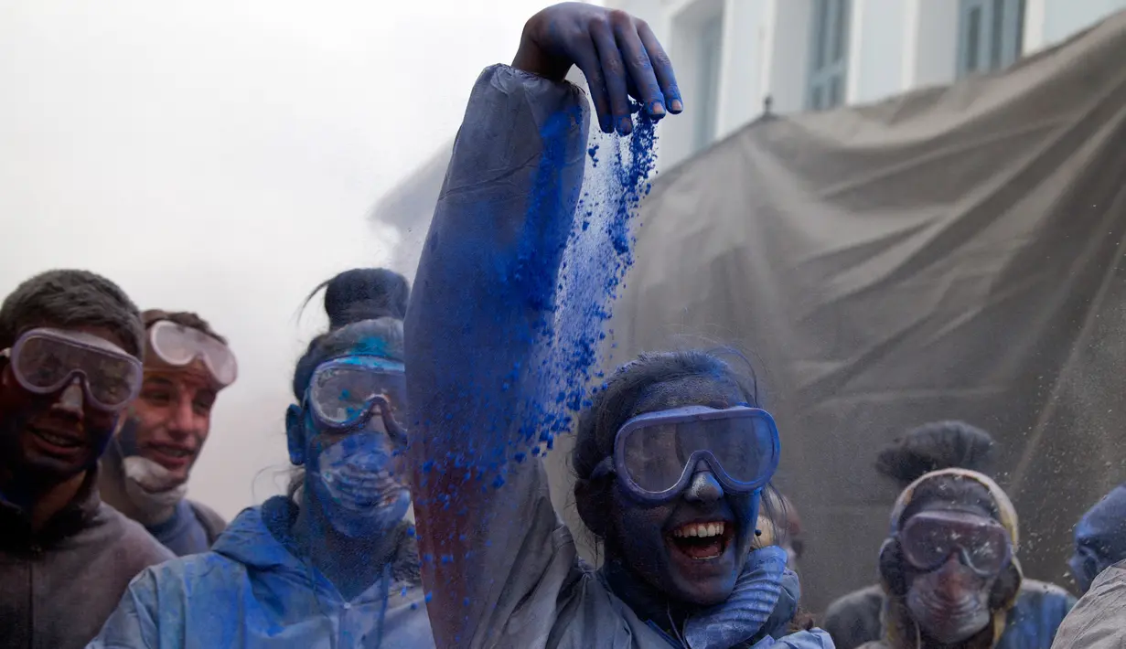 Seorang wanita menaburkan tepung berwarna saat mengikuti perang tepung terigu di kota pelabuhan Galaxidi, Yunani (19/2). Perang tepung yang berwarna-warni ini menandai akhir musim karnaval. (AP/Petros Giannakouris)