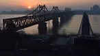Matahari terbit di belakang Jembatan Persahabatan yang membentang Sungai Yalu antara China dan Korea Utara terlihat dari kota Dandong di provinsi Liaoning timur laut China (22/2). (AFP Photo/Greg Baker)