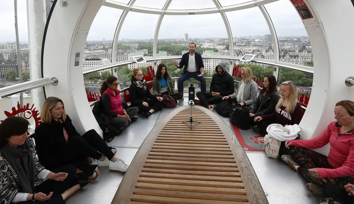Will Williams (tengah) memimpin meditasi di salah satu dari tiga kapsul London Eye di London, Inggris (15/5). Kegiatan meditasi ini bertujuan untuk mempromosikan Hari Meditasi Dunia. (AP Photo / Alastair Grant)