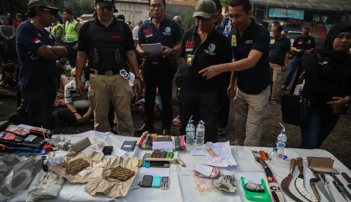 Petugas mengamati barang bukti yang berhasil didapat pada penggerebekan di Kampung Bahari, Tanjung Priok, Jakarta, Kamis (25/8). Pelaksanaan penggrebekan dilakukan di 8 titik berbeda yang sudah dipetakan Polres Jakarta Utara. (Liputan6.com/Faizal Fanani)
