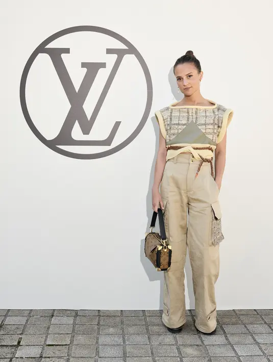 Alivia Vikander hadir dengan outfit bernuansa beige. Ia memadukan triangle neck vest dengan cargo pants berwarna senada. (Louis Vuitton)
