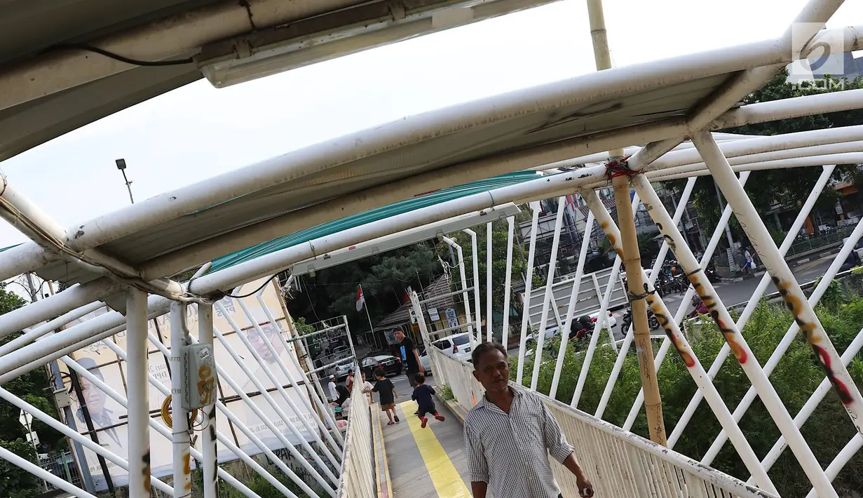 Pejalan kaki melintasi jembatan penyeberangan orang (JPO) Jayakarta yang atapnya rusak dan hilang di Menteng, Jakarta, Jumat (11/1). Kondisi atap JPO yang rusak akibat tertiup angin mengganggu kenyamanan pejalan kaki. (Liputan6.com/Immanuel Antonius)