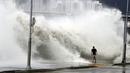 Seorang pria berjalan di pinggir pantai saat gelombang besar yang disebabkan oleh topan Chaba di Busan, Korea Selatan, 5 Oktober 2016. Topan Chaba berkecepatan 180 km per jam ini menyebabkan banjir bandang di Kota Busan. (REUTERS/Park Cheol-hong)