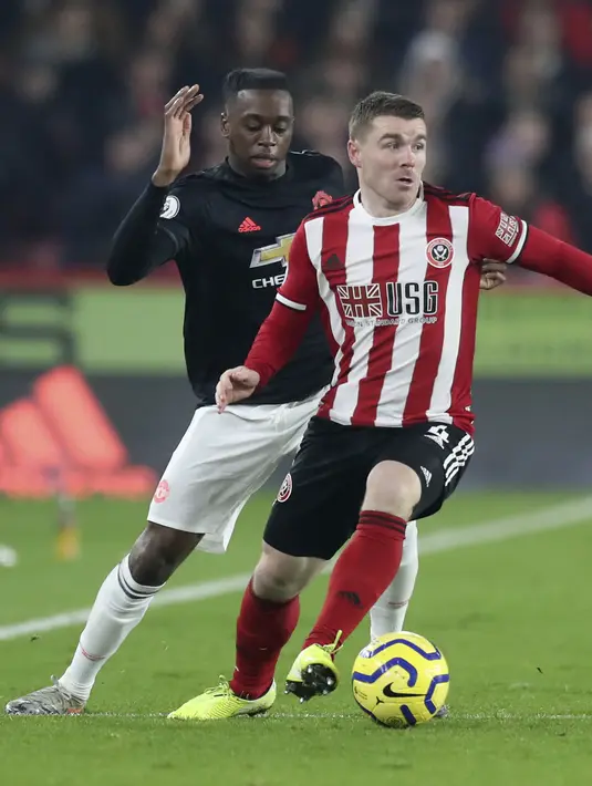 Bek Manchester United, Aaron Wan-Bissaka berusaha merebut bola yang dibawa gelandang Sheffield United, John Fleck pada pertandingan lanjutan Liga Inggris di Stadion Bramall Lane (24/11/2019). MU bermain imbang 3-3 atas Sheffield Unite. (AP Photo/Jon Super)