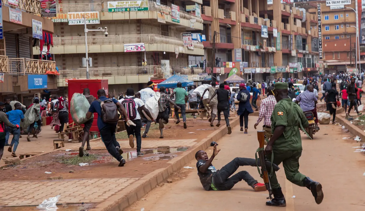 Seorang aparat kepolisian saat membubarkan orang-orang yang masih berkeliaran di Kampala, Uganda (26/3/2020). Pemerintah setempat juga menutup seluruh pintu perbatasan, kecuali untuk barang terbatas dan penerbangan darurat resmi sebagai upaya menekan penyebaran Covid-19. (AFP/Badru Katumba)