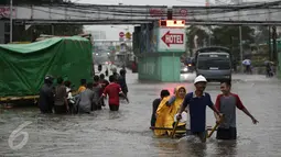Warga menaiki gerobak untuk menyeberangi banjir yang merendam Jalan Gunung Sahari, Jakarta Pusat, Selasa (21/2). Hujan yang turun sejak dini hari menyebabkan sejumlah ruas jalan terimbas banjir dan tak bisa dilalui kendaraan. (Liputan6.com/Faizal Fanani)