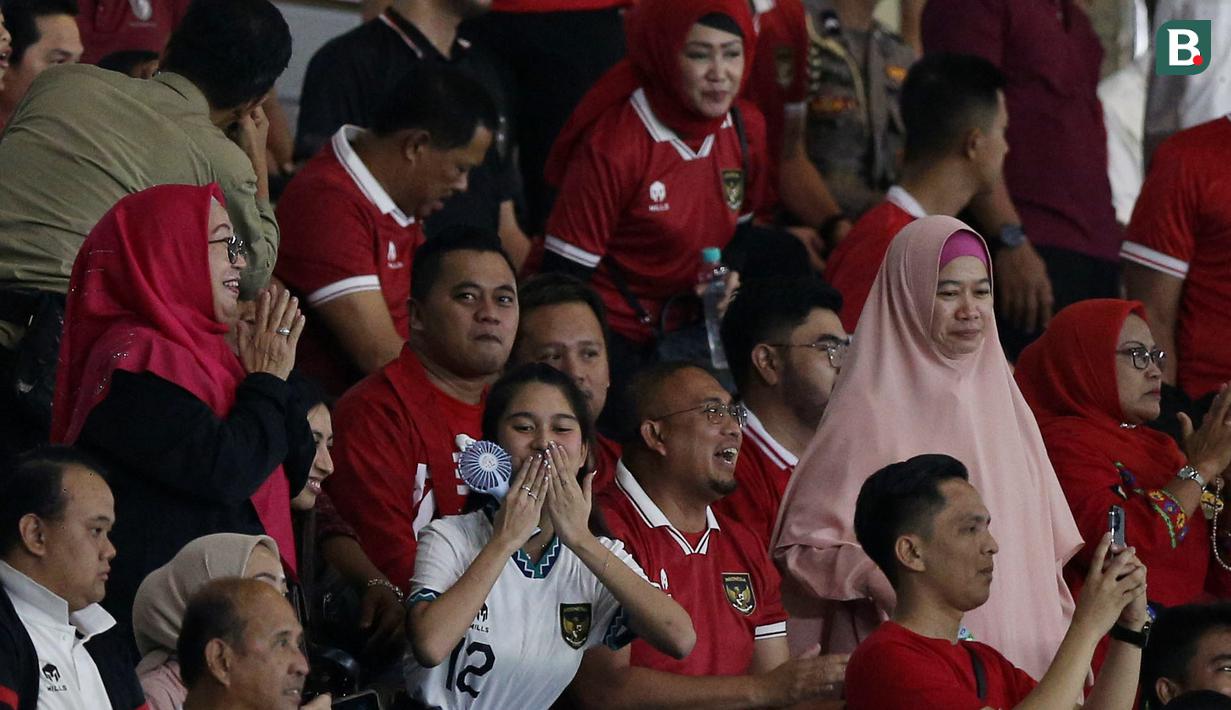 Momen Azizah Salsha (tengah bawah) saat memberikan isyarat cinta berupa kecupan jauh kepada suaminya, Pratama Arhan, yang merupakan bek Timnas Indoneisa U-23 setelah mencetak gol ke gawang Turkmenistan dalam pertandingan grup K Kualifikasi Piala Asia U-23 2024 yang berlangsung di Stadion Manahan, Solo, Selasa (12/9/2023). (Bola.com/Arief Bagus)