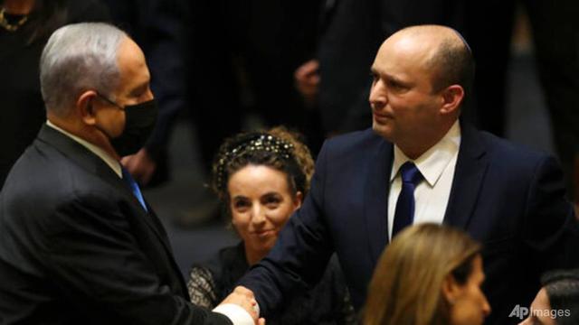 Perdana Menteri baru Israel Naftali Bennett berjabat tangan dengan Perdana Menteri Benjamin Netanyahu selama sesi Knesset di Yerusalem pada 13 Juni 2021. (Foto: AP/Ariel Schalit)
