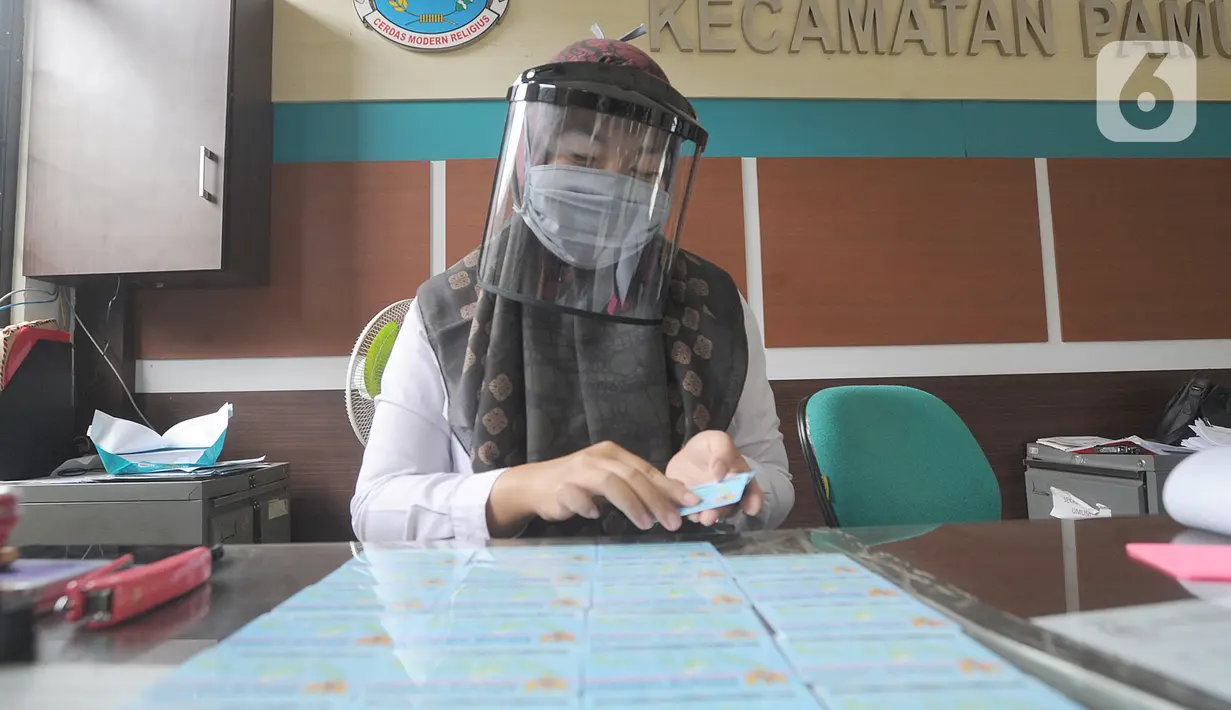 Petugas Dinas Kependudukan dan Catatan Sipil menggunakan pelindung wajah saat mengurus KTP-el di Kecamatan Pamulang, Tangerang Selatan, Rabu (3/6/2020). Sejumlah kantor pelayanan pemerintah melaksanakan protokol kesehatan yang ketat untuk memutus rantai penyebaran covid-19. (merdeka.com/Arie Basuki)
