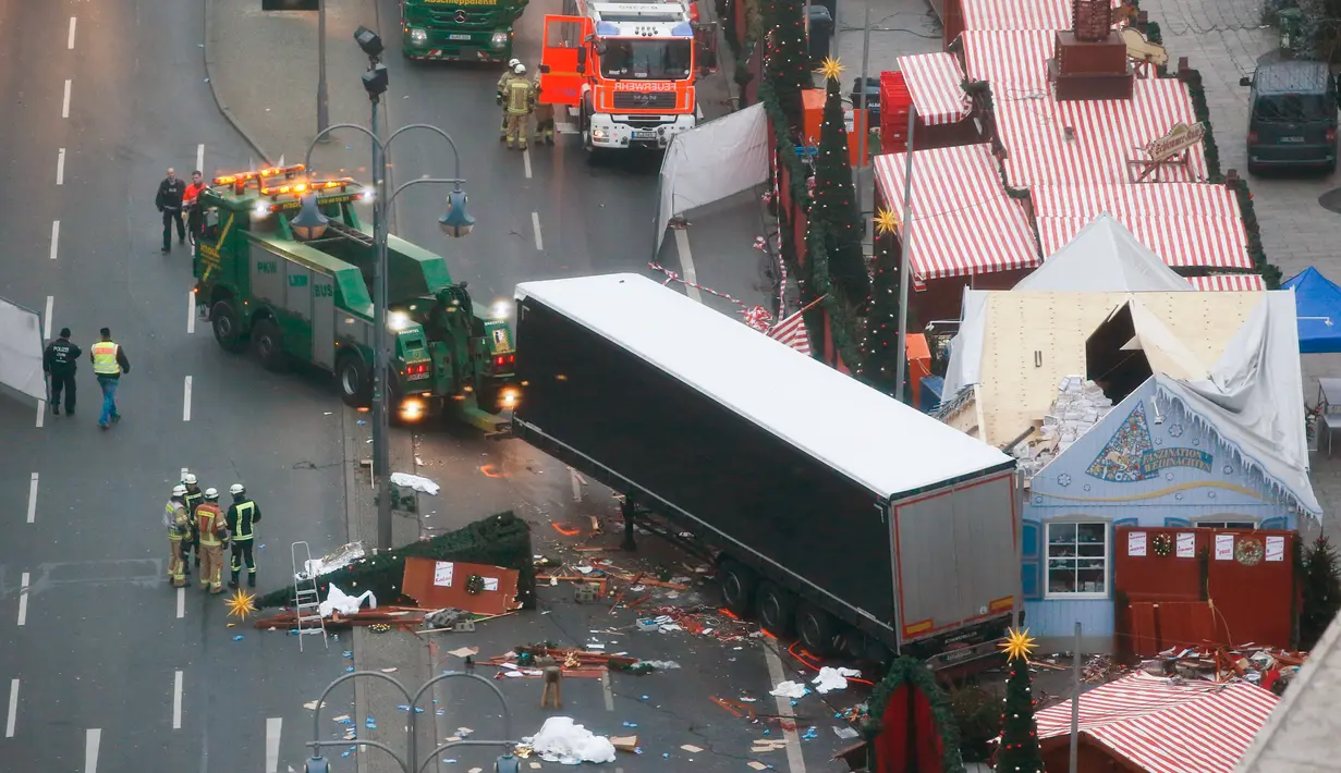 Petugas menderek truk yang menabrak Pasar Natal di Berlin, Jerman, Selasa (20/12). Akibat kejadian ini, dikabarkan 12 orang tewas dan 48 orang terluka. (REUTERS / Fabrizio Bensch)