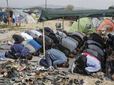 Para imigran terlihat khusyuk saat menggelar salat Jumat di sebuah kamp darurat perbatasan Yunani-Makedonia,desa Idomeni, Yunani (8/4). Meski tengah mencari perlindungan, mereka tak melalaikan kewajibannya sebagai seorang muslim. (REUTERS/Marko Djurica)