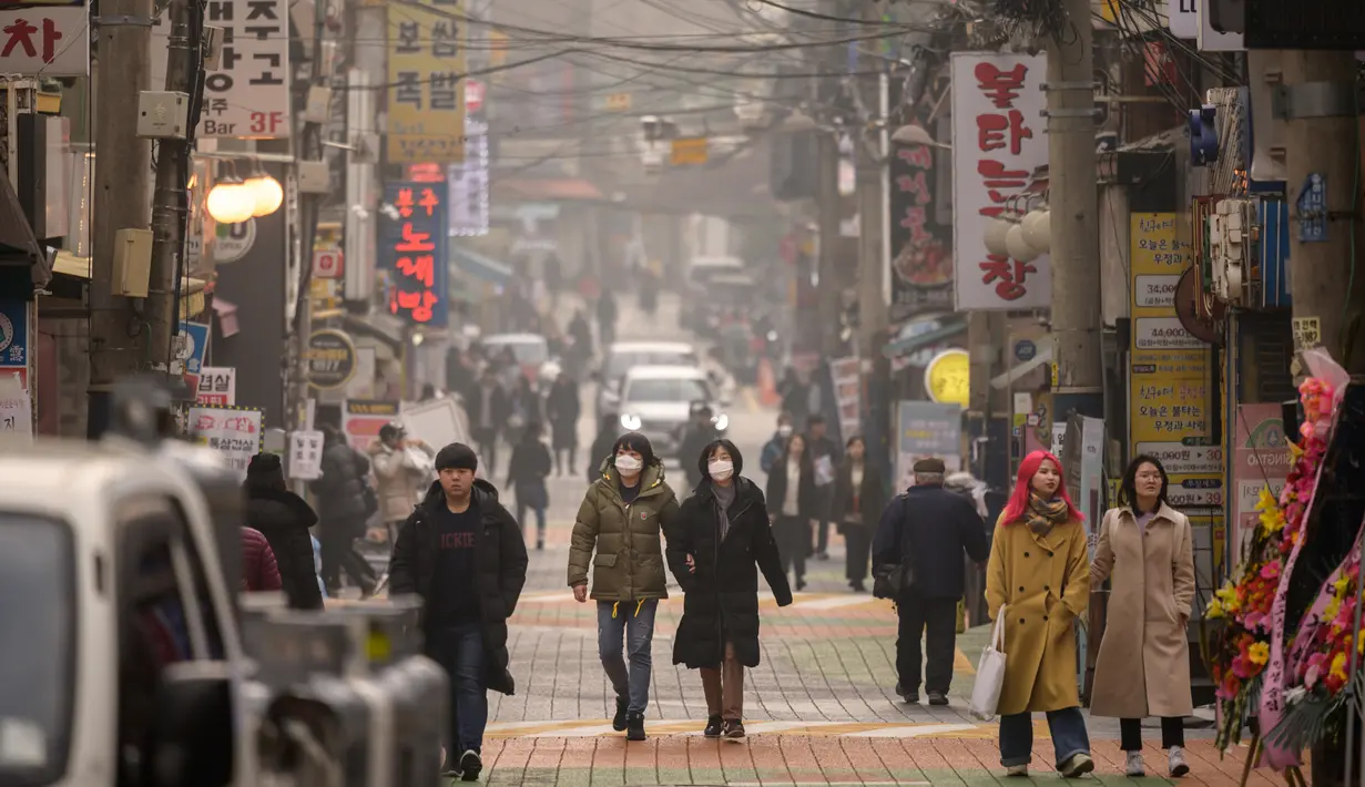 Warga mengenakan masker berjalan di jalanan selama kondisi cuaca yang tercemar di Seoul (10/12/2019). Kementerian Lingkungan Hidup Korsel menegakkan serangkaian tindakan darurat untuk mengurangi polusi debu halus, termasuk melarang kendaraan tertentu dari jalan pusat kota. (AFP Photo/Ed Jones)
