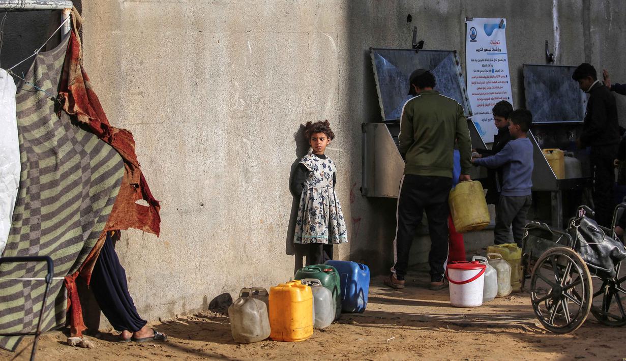 Sementara itu, pada konferensi pers tengah pekan Perserikatan Bangsa Bangsa (PBB) di Jenewa, Juru bicara UNICEF, James Elder, mengatakan bahwa hampir dua setengah tahun serangan Israel terhadap pendidikan di Gaza telah menempatkan seluruh generasi anak-anak dalam bahaya besar. Tampak dalam foto, seorang gadis kecil mengantre sementara yang lain mengisi wadah dengan air dari sumur umum, di kamp pengungsi Palestina Nuseirat di utara Deir al-Balah, Jalur Gaza tengah pada 29 Januari 2026. (EYAD BABA/AFP)