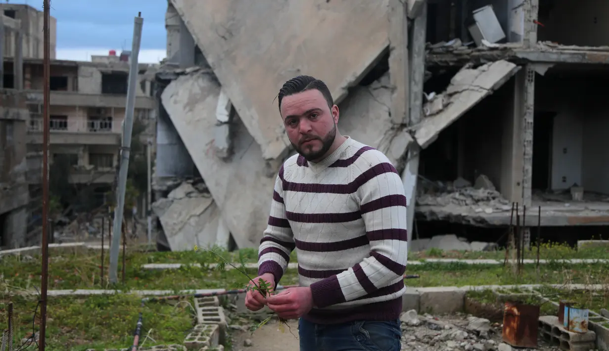 Mohamed Ataya atau yang dikenal sebagai "Abu Maher" menanam tanaman di atap sebuah gedung yang rusak di Ghouta, pinggiran Damaskus, Suriah (3/3). (AFP/Amer Almohibany)