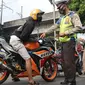 Petugas Kepolisian melakukan razia pengendara motor dengan knalpot bising di kawasan Monumen Nasional (Monas), Jakarta, Minggu (7/3/2021). Razia knalpot bising tersebut guna memberikan kenyamanan bagi warga yang hendak berolahraga di area tersebut. (Liputan6.com/Herman Zakharia)