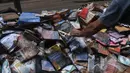 Seorang pria mengambil buku rusak yang ditinggalkan di jalan setelah hujan lebat membanjiri toko buku di Petropolis, Brasil, 19 Februari 2022. Sebanyak 136 jenazah telah diidentifikasi hingga saat ini, menurut pejabat pertahanan sipil. (MAURO PIMENTEL/AFP)