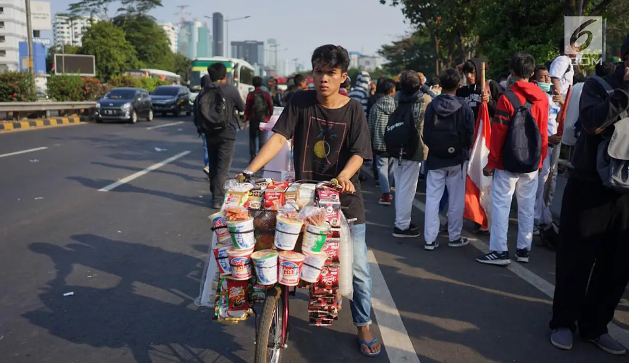 Seorang pedagang asongan berjualan di antara massa aksi di jalan tol dalam kota yang berada di depan Gedung DPR RI, Jakarta, Senin (30/9/2019). Adanya aksi unjuk rasa di sekitar lokasi dimanfaatkan para pedagang asongan untuk mencari rezeki. (Liputan6.com/Immanuel Antonius)