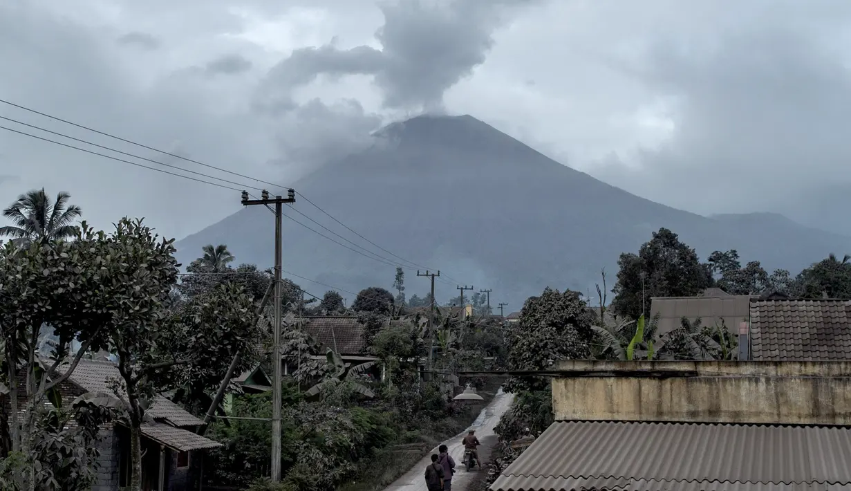 Gunung Semeru menjulang di atas desa Lumajang, Jawa Timur, setelah meletus sehari sebelumnya, Minggu (17/1/2021). Gunung Semeru kembali erupsi dan mengeluarkan awan panas guguran sejauh 4,5 kilometer pada Sabtu (16/1). (Juni Kriswanto / AFP)