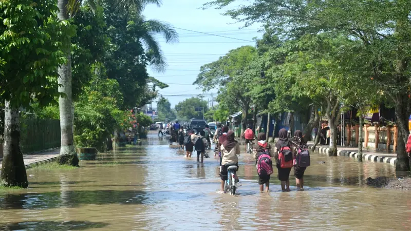 Anak sekolah melintasi genangan banjir di Sidareja, Cilacap, Jawa Tengah. (Foto: Liputan6.com/Muhamad Ridlo)