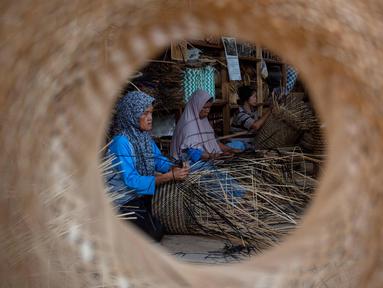 Para pekerja membuat keranjang dari bambu di tempat kerja mereka, Sleman, Yogyakarta pada 9 April 2025. (DEVI RAHMAN/AFP)