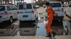 Petugas Basarnas melintas dekat mobil jenazah yang disiagakan di Posko Evakuasi Tanjung Priok, Jakarta, Senin (29/10). Posko itu menjadi tempat transit korban jatuhnya pesawat Lion Air JT610 di laut utara Karawang, Jawa Barat. (Liputan6.com/Faizal Fanani)