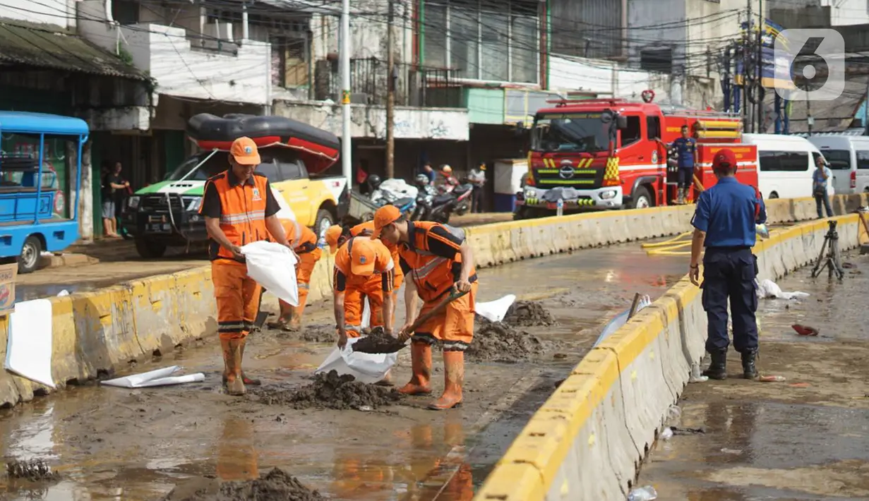 Petugas Penanganan Prasaran dan Sarana Umum (PPSU) membersihkan lumpur yang mengendap di sepanjang Jalan Jatinegara Barat, Kampung Melayu, Jakarta Timur, Kamis (2/1/2020). Petugas melakukan bersih-bersih menyusul mulai surutnya banjir di kawasan tersebut. (Liputan6.com/Immanuel Antonius)