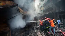 Petugas pemadam kebakaran berusaha memadamkan api setalah api melahap gedung apartemen yang juga digunakan sebagai gudang bahan kimia di Dhaka (21/2). Setidaknya 69 orang tewas dalam kebakaran besar tersebut. (AFP Photo/Munir Uz Zaman)