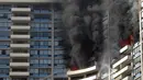Petugas pemadam kebakaran menyemprotkan air untuk memadamkan api saat terjadi kebakaran di apartemen Marco Polo, Honolulu (14/7). Setidaknya tiga orang tewas akibat kebakaran yang terjadi di apartemen tersebut. (AP Photo / Marco Garcia)