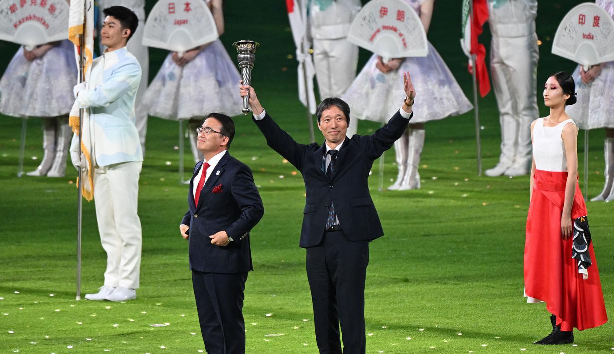 Gubernur di prefektur Aichi, Jepang, Ohmura Hideaki (kiri) dan wakil walikota Nagoya, Jepang, Nakata Hideo (kanan) mengambil bagian dalam penyerahan obor pada upacara penutupan Asian Games 2022 yang berlangsung di Hangzhou Olympic Sports Centre Stadium, Hangzhou, China pada Minggu (08/10/2023). Jepang menjadi tuan rumah Asian Games selanjutnya yang akan berlangsung pada 2026 mendatang. (AFP/Jung Yeong-je)