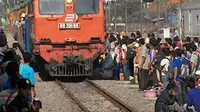 Calon penumpang berdiri tak jauh dari rel saat kereta api (KA) melintas di depannya di Stasiun Pasar Turi Surabaya, Minggu (2/7). (Antara)