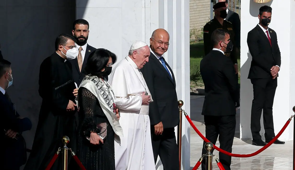 Paus Fransiskus (tengah) berjalan dengan Presiden Irak Barham Salih menuju pesawatnya usai mengakhiri kunjungannya ke Irak di Bandara Baghdad, Irak, Senin(8/3/2021). Paus meninggalkan Irak usai membawa harapan kepada minoritas Kristen yang terpinggirkan di negara itu. (AP Photo/Khalid Mohammed)