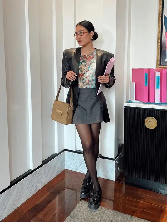Alika Islamadina tampil dengan gaya office look mengenakan mini skirt abu-abu dipadukan blazer hitam lester dan inner abstrak. Serta mengenakan stocking hitam senada dengan sepatu oxfordnya. [@alikaislamadima]