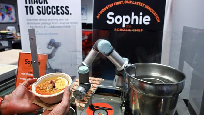 Robot koki bernama Sophie meracik semangkuk laksa saat demonstrasi memasak di Singapura pada 26 Juli 2019. Untuk memesan laksa ini, calon pembeli cukup memilih jenis mie yang diinginkan dan tambahannya seperti potongan ikan olahan dan toge. (Roslan RAHMAN / AFP)