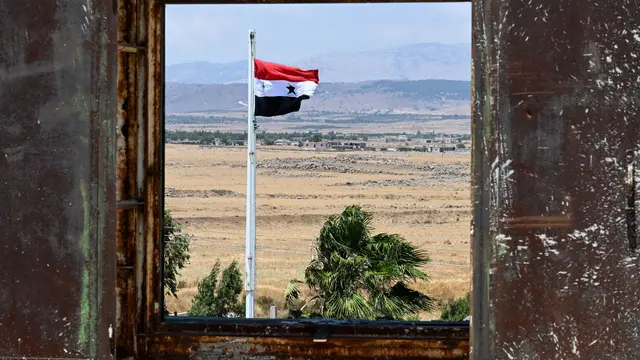 Bendera Suriah berkibar di Kota Quneitra menghadap sisi Dataran Tinggi Golan yang dianeksasi Israel. (AP/Louiai Beshara)