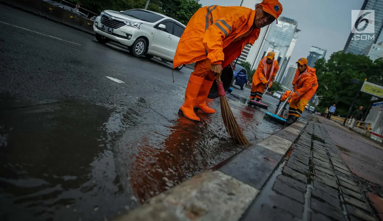 Petugas Dinas Kebersihan membersihkan genangan air usai hujan di kawasan jalan Sudirman, Jakarta, Rabu (22/11). Buruknya sistem drainase membuat petugas membersihkan genangan setiap kali hujan, meski dengan peralatan seadanya. (Liputan6.com/Faizal Fanani)
