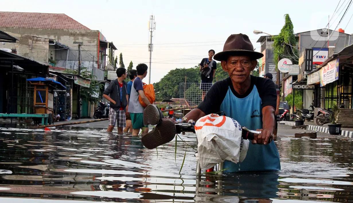 Warga melintasi banjir yang merendam perumahan Villa Mutiara Pluit, Tangerang, Banten, Senin (3/2/2020). Banjir disebabkan jebolnya tanggul sungai di sekitar kawasan tersebut. (merdeka.com/Magang/Muhammad Fayyadh)