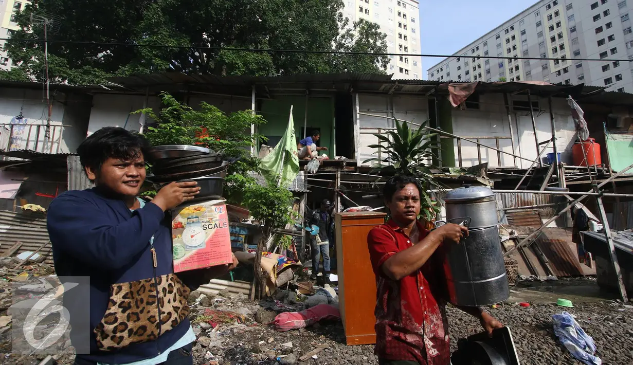 Warga membawa barang berharga saat alat berat merobohkan bangunan di kawasam Rawajati, Jakarta, Kamis (1/9). Penertiban tersebut menyebabkan warga terpaksa menyelamatkan barang berharga mereka ke tepi rel kereta api. (Liputan6.com/Immanuel Antonius)